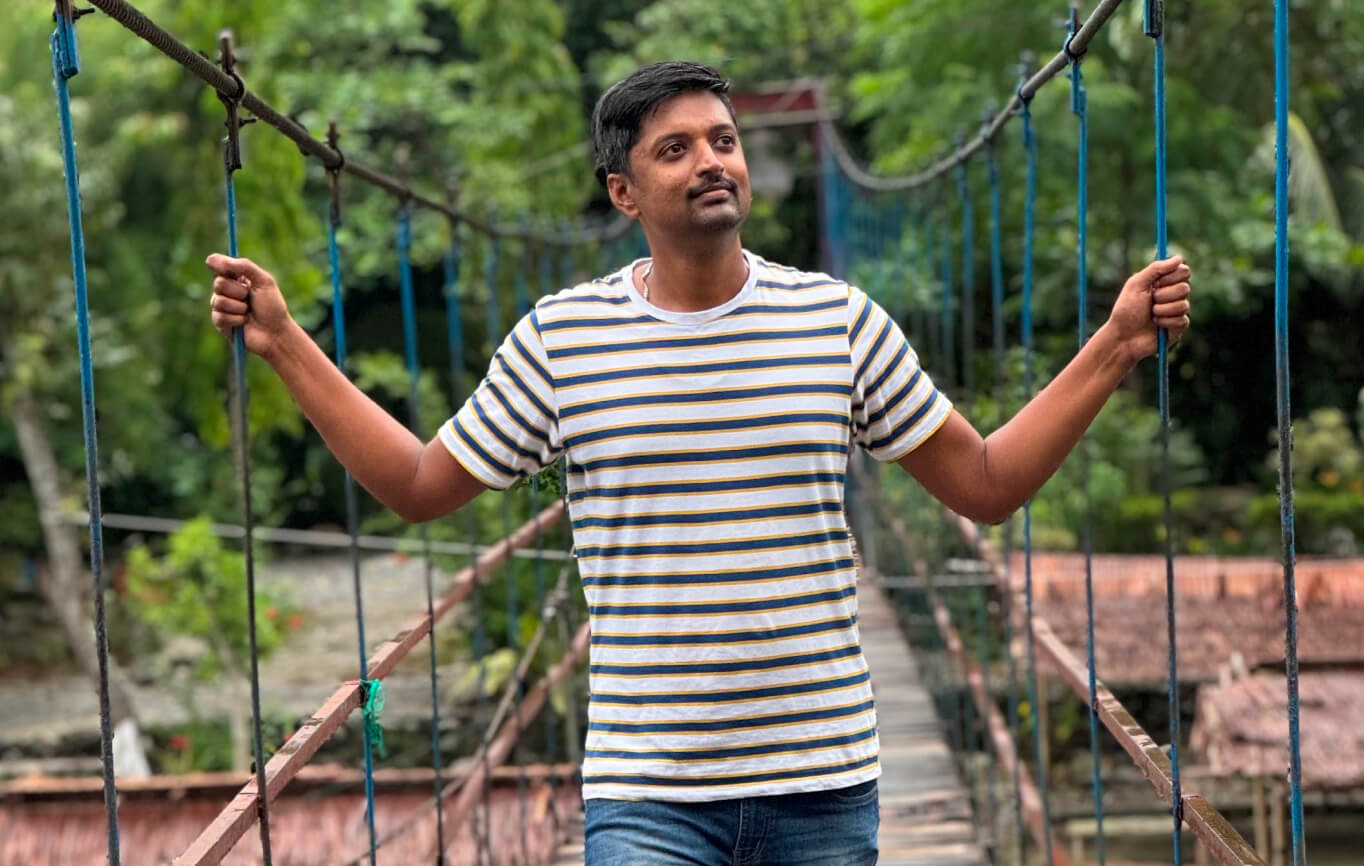 Vasanth crossing a suspension bridge surrounded by forest