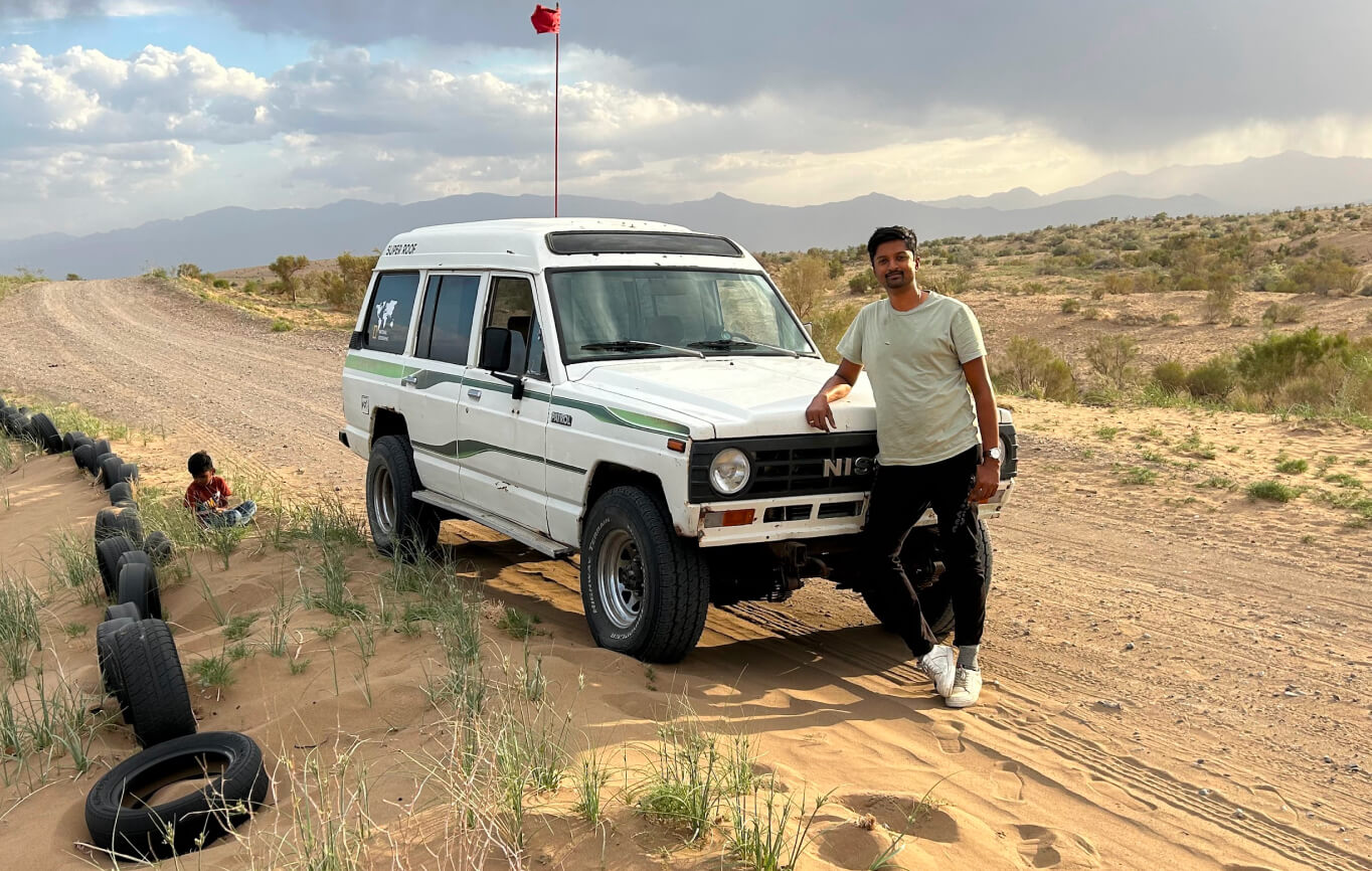 Vasanth beside an off-road vehicle in a desert landscape
